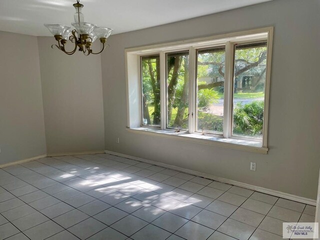 unfurnished room featuring plenty of natural light, light tile patterned flooring, and a chandelier