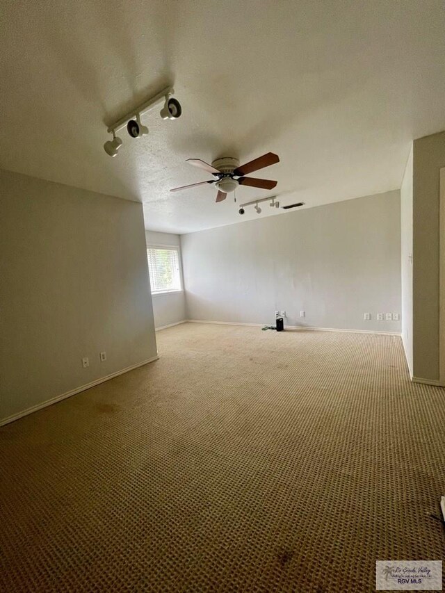 carpeted empty room featuring a textured ceiling, ceiling fan, and rail lighting