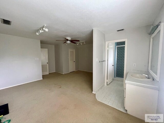 interior space with ceiling fan, a textured ceiling, and vanity