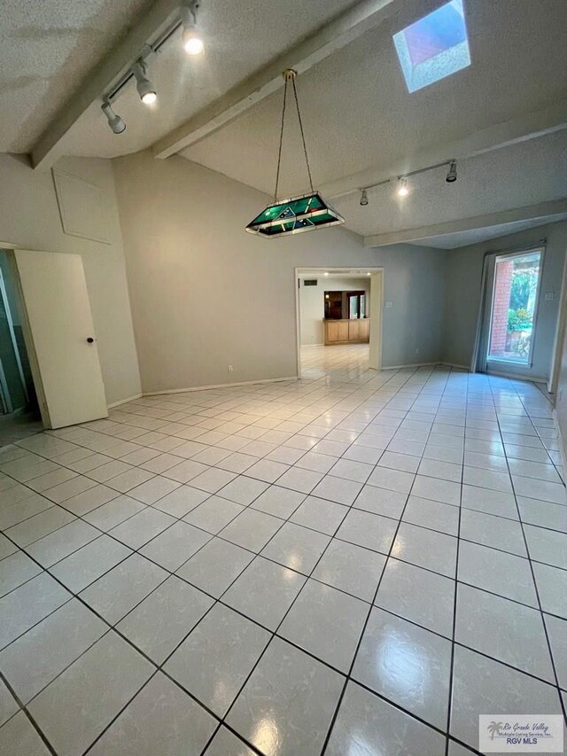 unfurnished living room featuring light tile patterned floors, a textured ceiling, rail lighting, and lofted ceiling with skylight