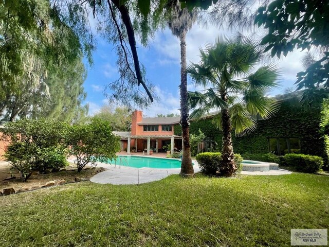 view of pool featuring an in ground hot tub, a yard, and a patio area