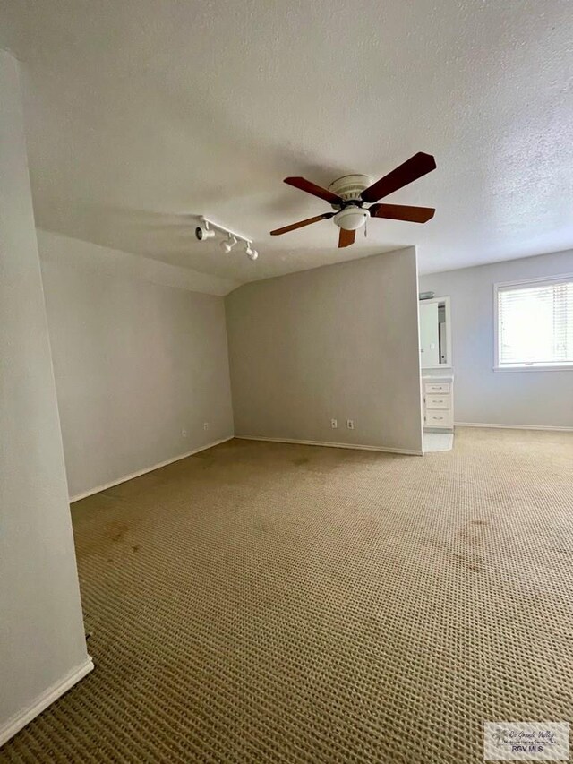 carpeted empty room with rail lighting, ceiling fan, and a textured ceiling