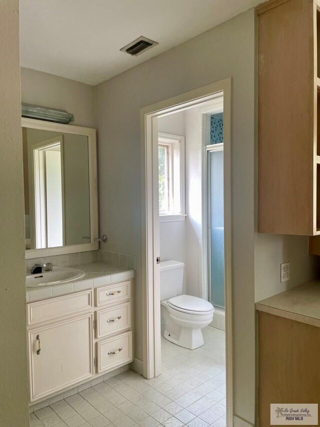 bathroom with toilet, vanity, tile patterned floors, and walk in shower