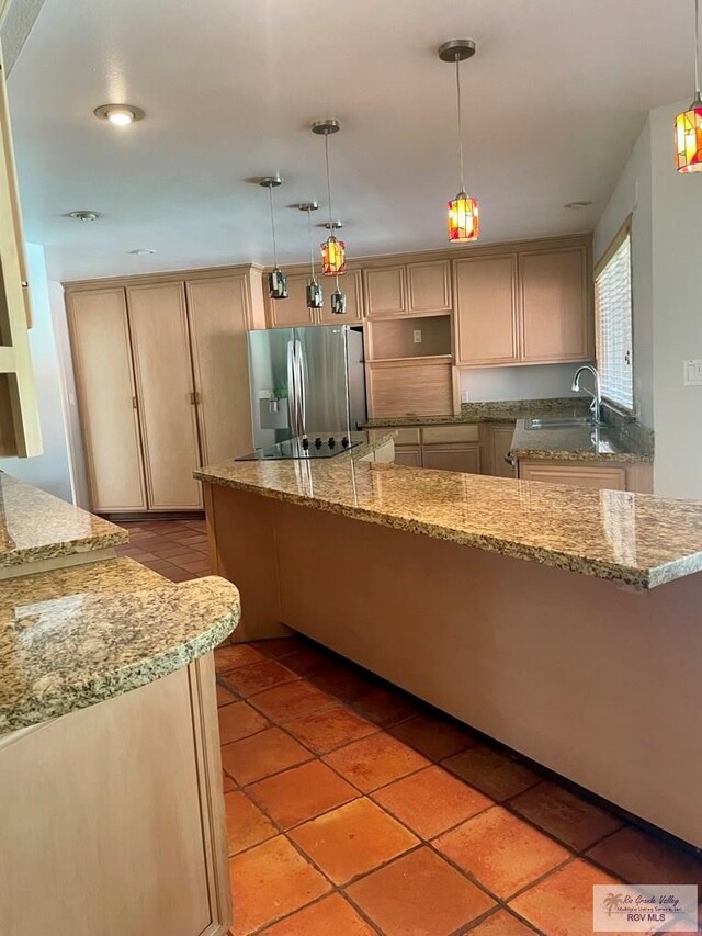 kitchen featuring light brown cabinetry, decorative light fixtures, stainless steel refrigerator with ice dispenser, and sink