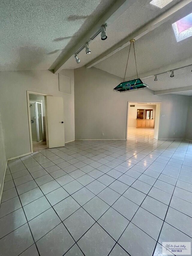 tiled spare room with a textured ceiling and vaulted ceiling with skylight