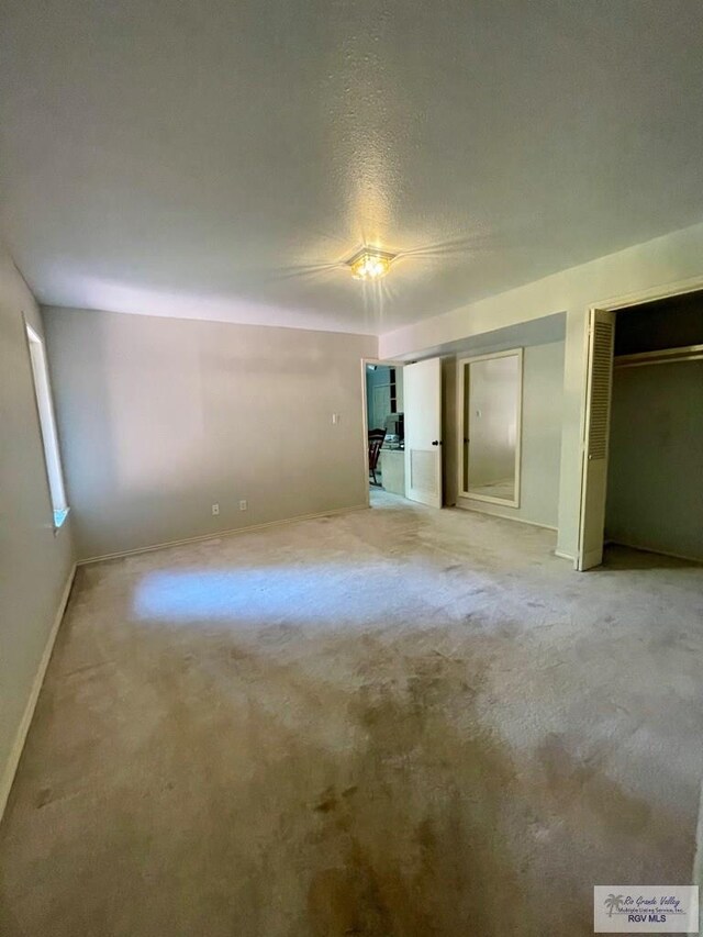 unfurnished bedroom featuring multiple closets, ceiling fan, carpet, and a textured ceiling