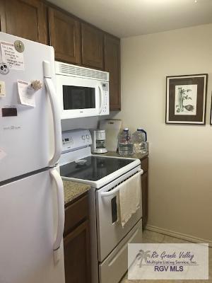 kitchen featuring dark stone countertops, light tile patterned floors, white appliances, and dark brown cabinets