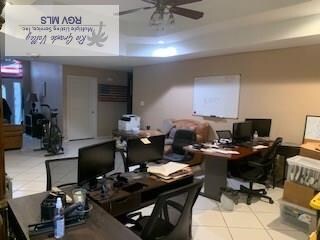 tiled home office featuring a raised ceiling and ceiling fan