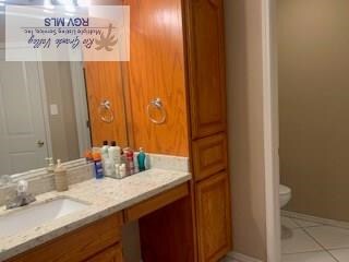 bathroom with toilet, vanity, baseboards, and tile patterned floors