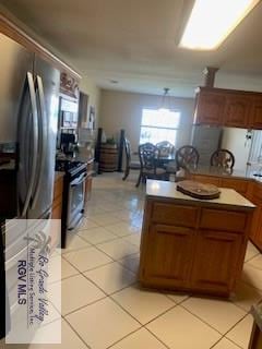 kitchen featuring stainless steel fridge, light tile patterned flooring, and range with electric cooktop