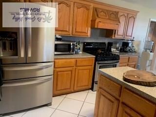 kitchen featuring brown cabinets, light tile patterned floors, stainless steel appliances, and light countertops