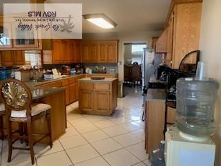 kitchen with a kitchen island, light tile patterned floors, and a breakfast bar area