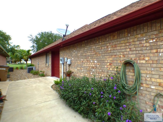 3319 Country Club Dr, Edinburg, TX 78542 - view of side of home featuring brick siding, central air condition unit, roof with shingles, concrete driveway, and an attached garage