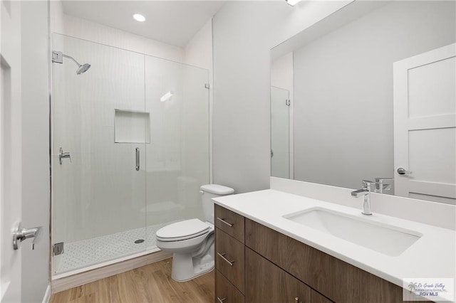 bathroom featuring vanity, wood-type flooring, an enclosed shower, and toilet