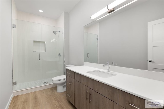 bathroom featuring wood-type flooring, vanity, toilet, and a shower with shower door