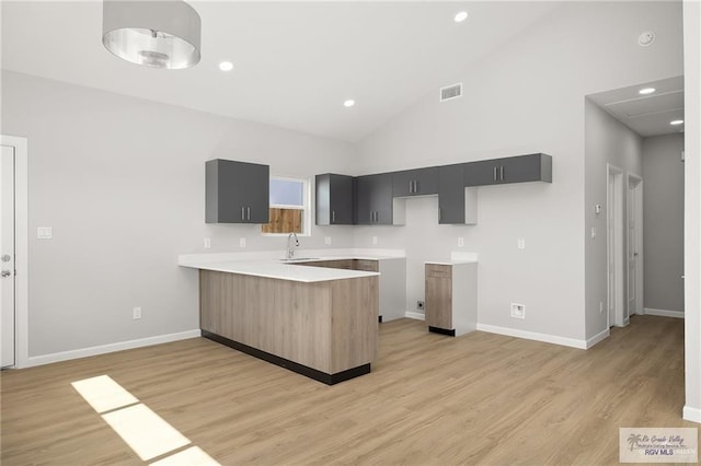 kitchen featuring kitchen peninsula, sink, high vaulted ceiling, and light hardwood / wood-style floors