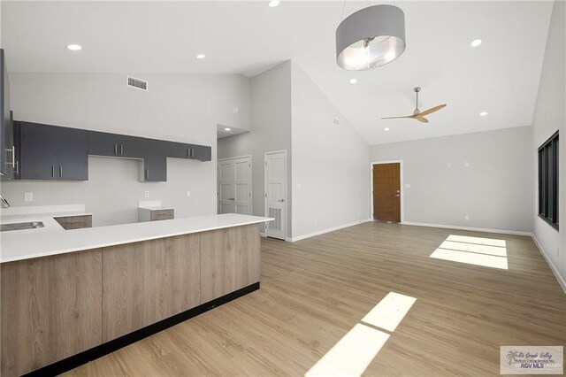 kitchen with ceiling fan, sink, high vaulted ceiling, decorative light fixtures, and light wood-type flooring