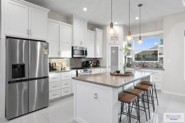 kitchen with white cabinetry, a center island, stainless steel appliances, tasteful backsplash, and pendant lighting