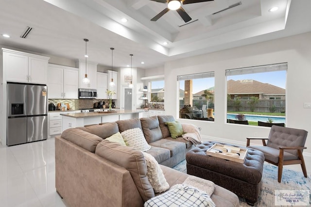 living room with ceiling fan, light tile patterned flooring, and a tray ceiling