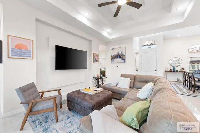 living room with ceiling fan with notable chandelier, a raised ceiling, and light tile patterned floors