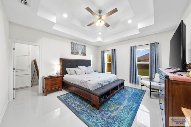 tiled bedroom featuring ceiling fan and a tray ceiling