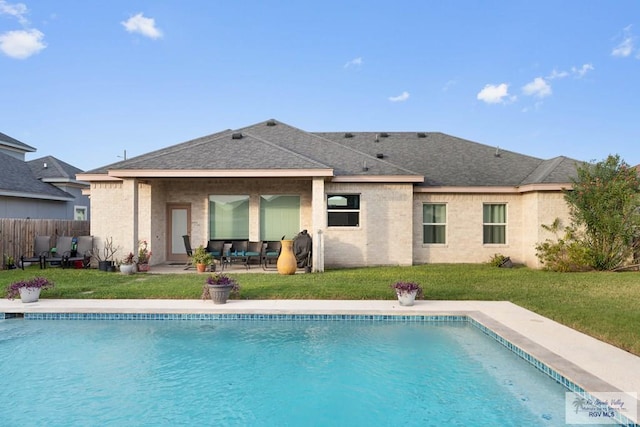 rear view of property with a fenced in pool, a patio area, and a lawn