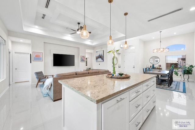 kitchen featuring a tray ceiling, white cabinetry, a center island, and decorative light fixtures