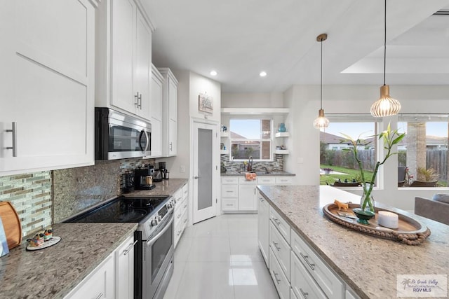 kitchen featuring decorative backsplash, a wealth of natural light, appliances with stainless steel finishes, light stone counters, and white cabinetry