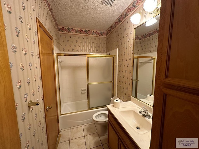 full bathroom with bath / shower combo with glass door, vanity, a textured ceiling, tile patterned flooring, and toilet