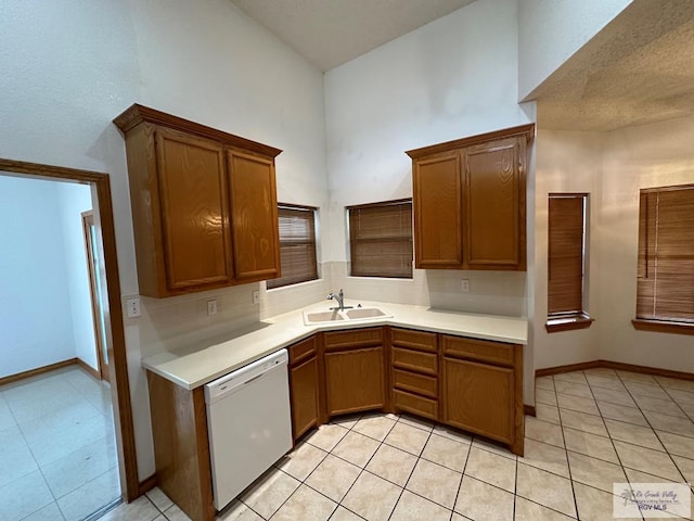 kitchen featuring dishwasher, a towering ceiling, light tile patterned floors, and sink