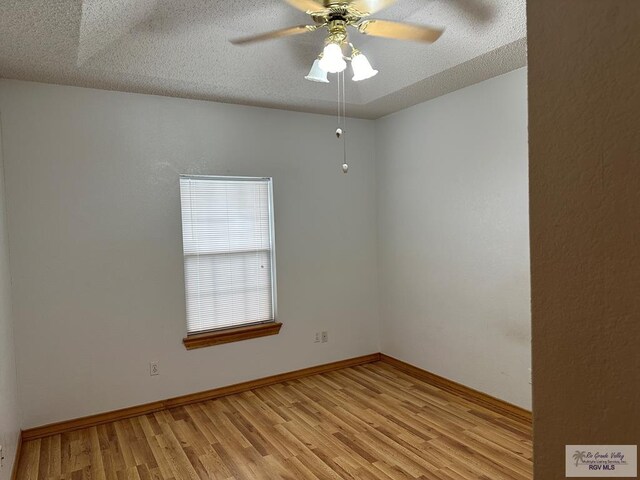 empty room featuring a textured ceiling, light wood-type flooring, and ceiling fan