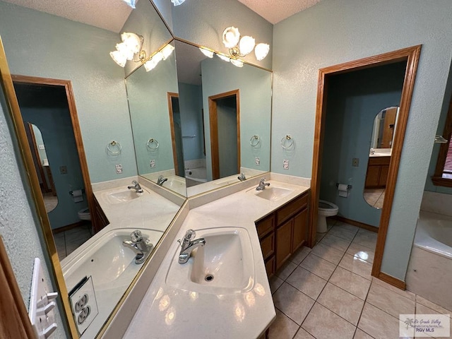 bathroom featuring tile patterned flooring, vanity, a textured ceiling, and toilet