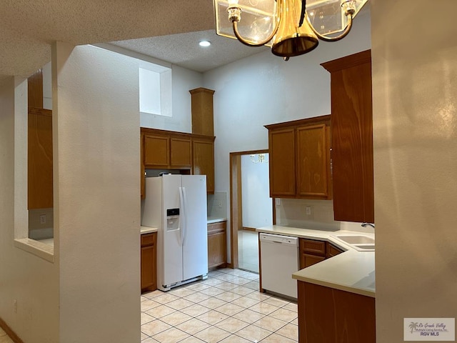 kitchen with a textured ceiling, decorative light fixtures, white appliances, and an inviting chandelier