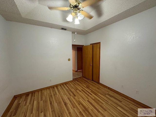 unfurnished room with ceiling fan, light hardwood / wood-style floors, and a textured ceiling