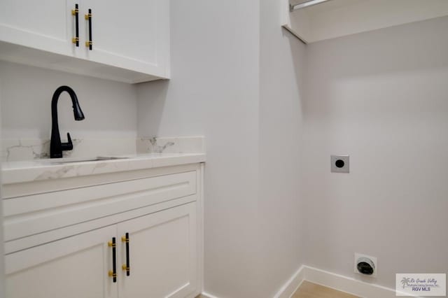 clothes washing area with cabinets, electric dryer hookup, and sink