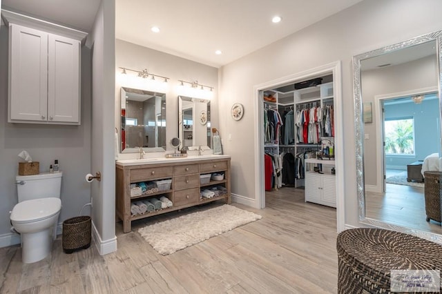 38 Spoonbill Cove Rd, Laguna Vista, TX 78578 - full bathroom with double vanity, wood finished floors, baseboards, toilet, and recessed lighting