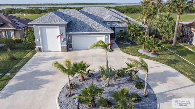38 Spoonbill Cove Rd, Laguna Vista, TX 78578 - view of front facade with roof with shingles, a garage, concrete driveway, stucco siding, and a front lawn