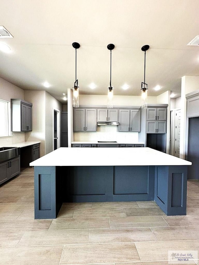 kitchen featuring a spacious island, gray cabinets, and decorative light fixtures