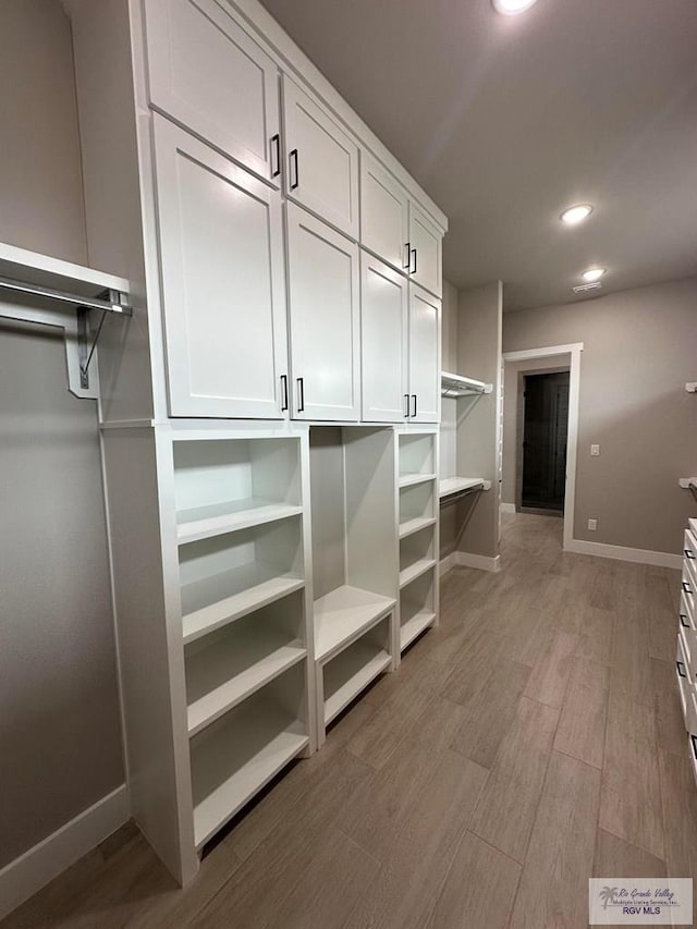 walk in closet with light hardwood / wood-style floors