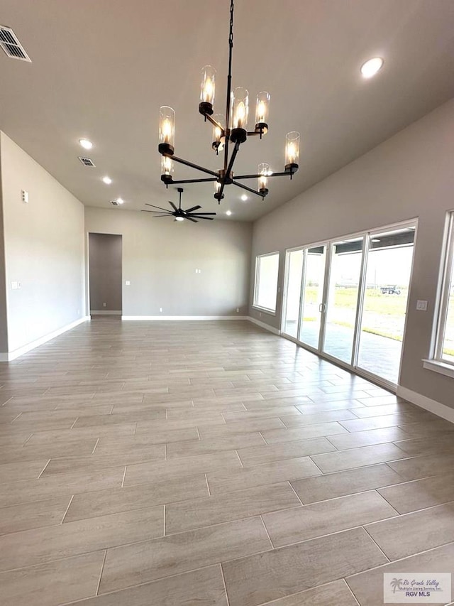 empty room featuring ceiling fan with notable chandelier