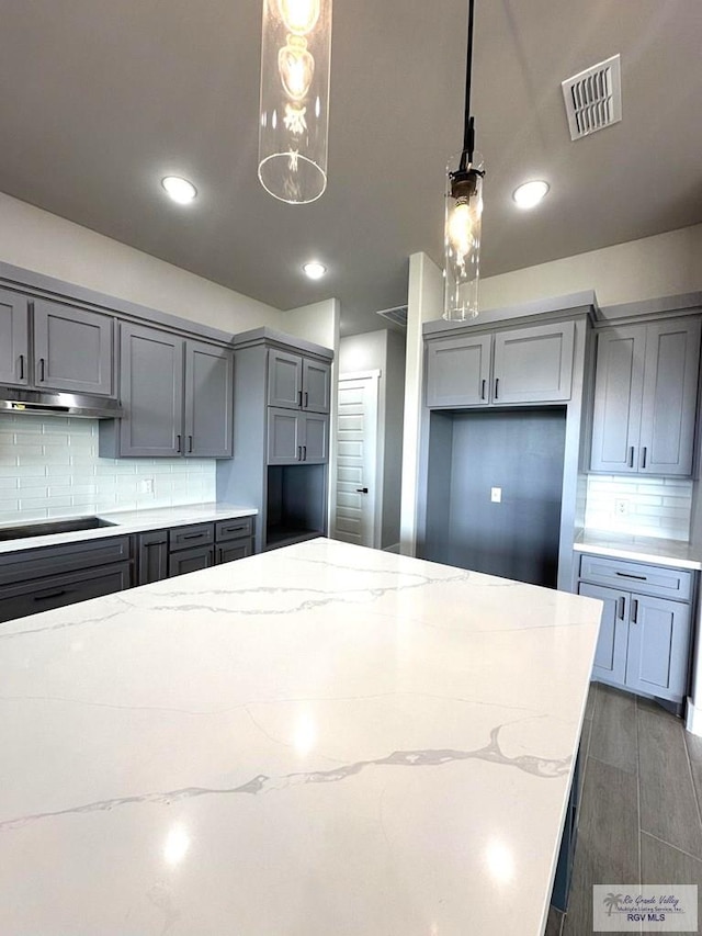 kitchen featuring gray cabinetry, pendant lighting, black electric cooktop, and light stone counters