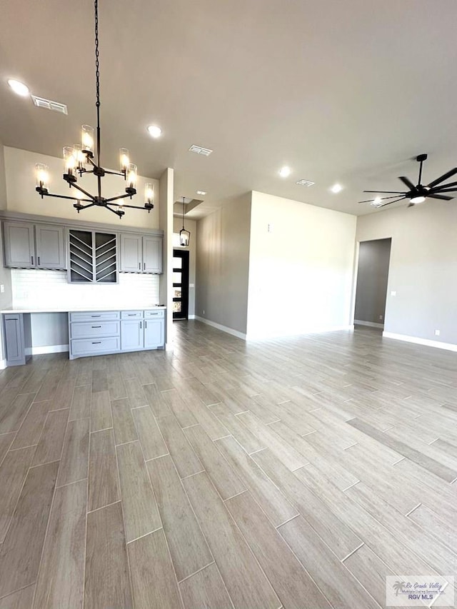 unfurnished living room with ceiling fan with notable chandelier