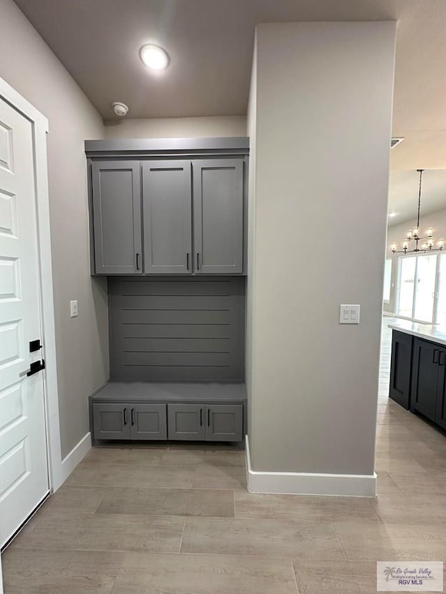 mudroom featuring light wood-type flooring and an inviting chandelier