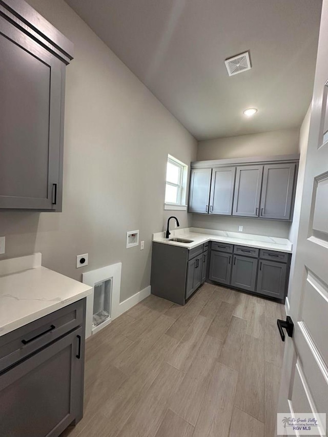 kitchen featuring sink, gray cabinets, light stone countertops, and light hardwood / wood-style floors