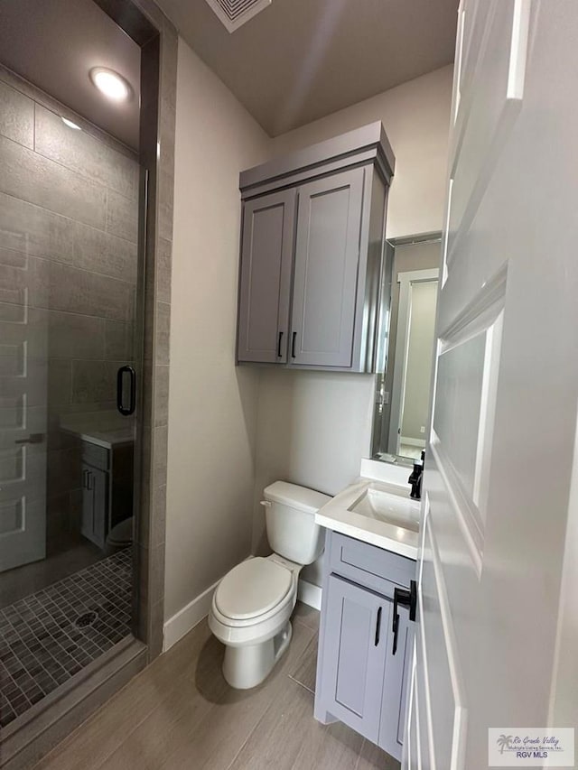 bathroom with vanity, toilet, and a shower with shower door