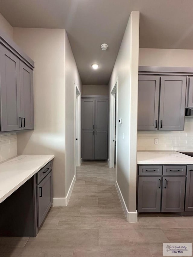 kitchen with gray cabinets, light hardwood / wood-style floors, and tasteful backsplash