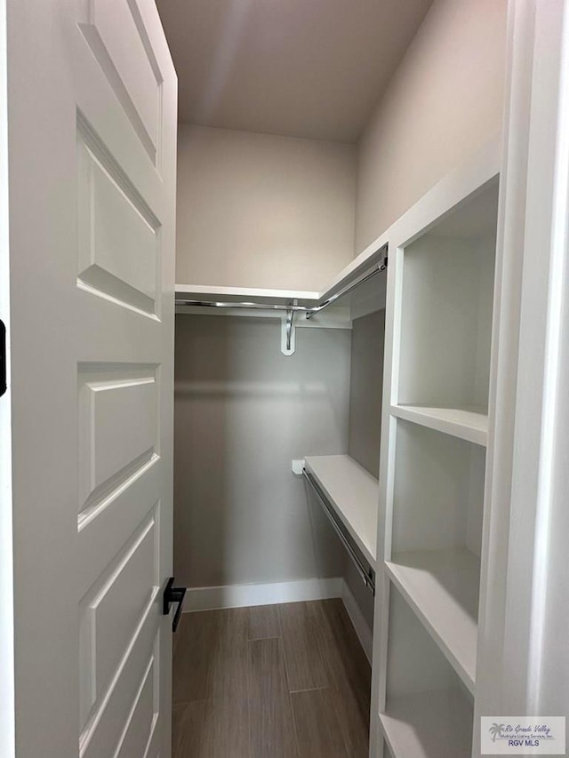 spacious closet with dark hardwood / wood-style floors