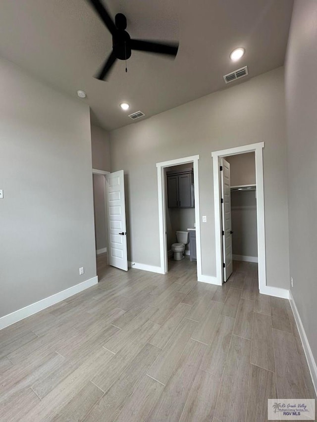 unfurnished bedroom with light hardwood / wood-style floors, a walk in closet, a closet, and ensuite bathroom