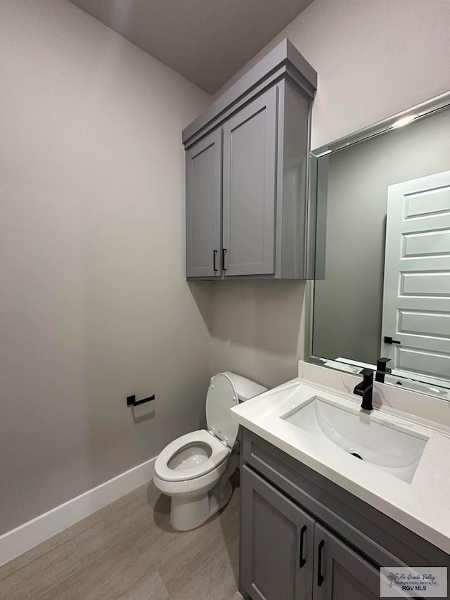 bathroom with vanity, toilet, and hardwood / wood-style floors