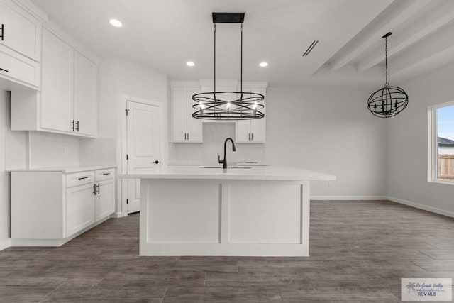 kitchen featuring white cabinetry, a sink, a chandelier, light countertops, and baseboards